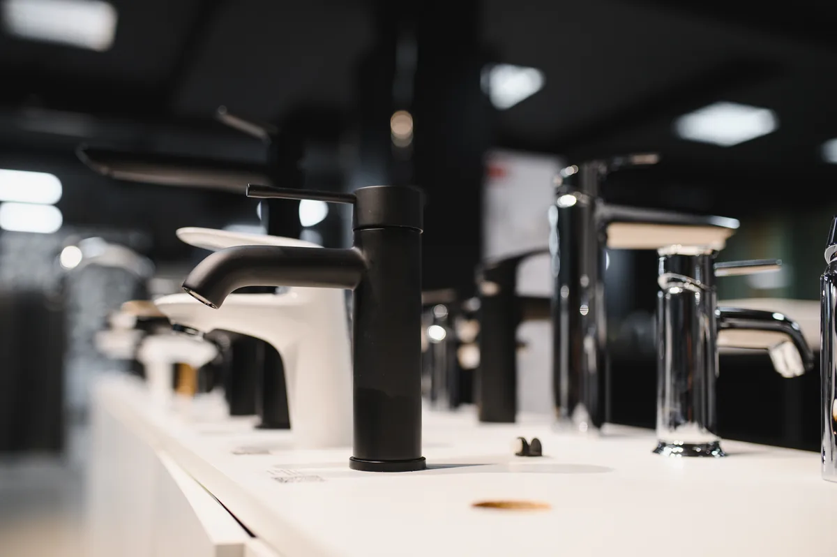 Rubinetti di design allineati su un espositore da showroom, finiture nero opaco e cromo lucido a confronto per il bagno