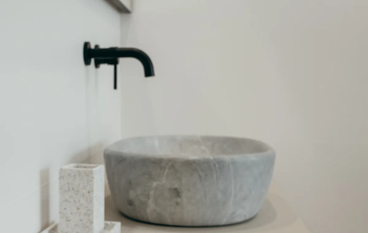 Rubinetti di design, miscelatore lavabo a muro nero opaco abbinato a un lavabo in pietra in un bagno contemporaneo