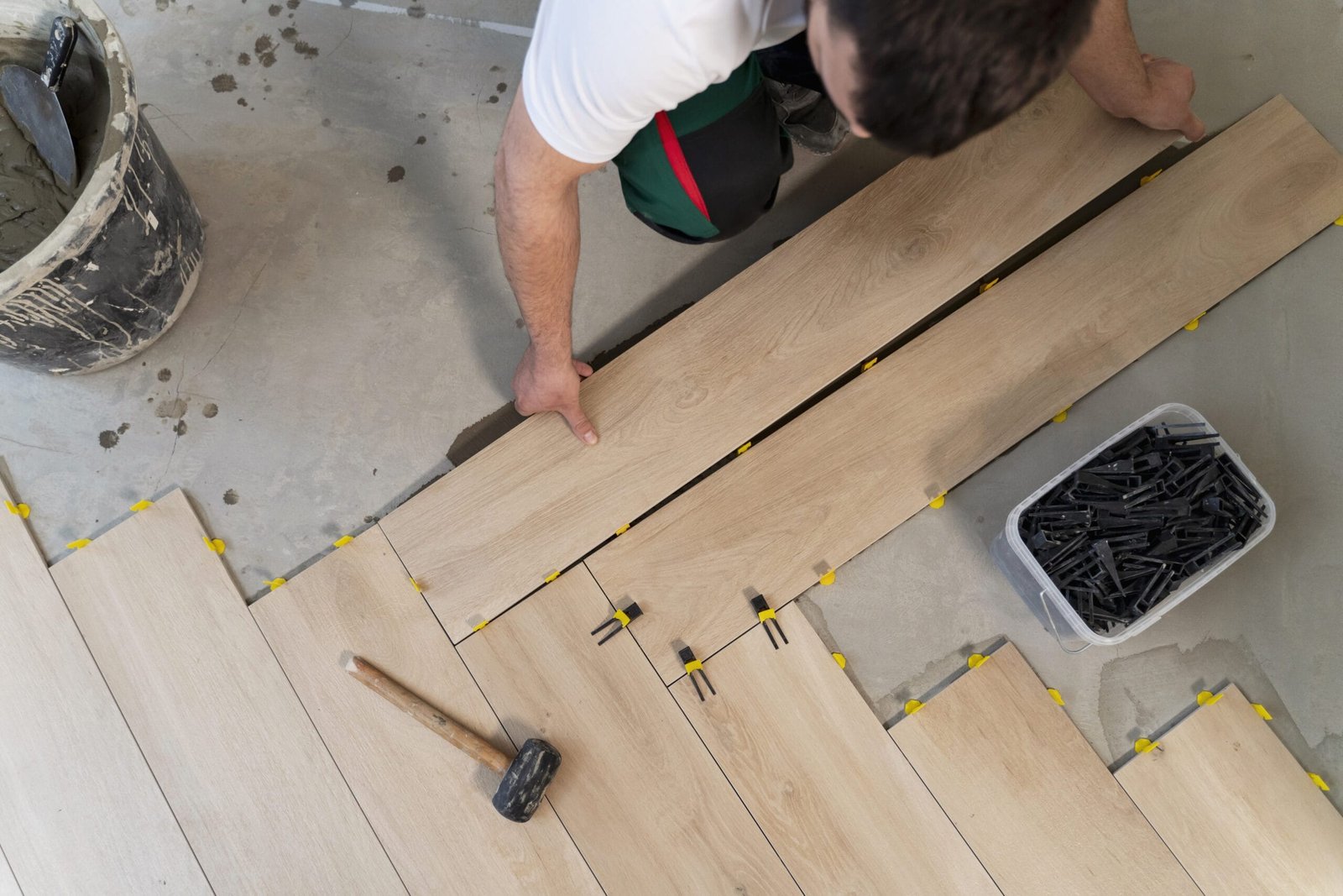 Parquet o Gres Porcellanato Effetto Legno, Quale Scegliere e Perché? top view man tiling floor scaled 1