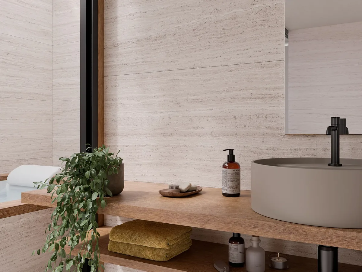 Gres effetto travertino Olimpo Avorio 60x120 posato a parete in un bagno moderno con lavabo tondo e mensola in legno