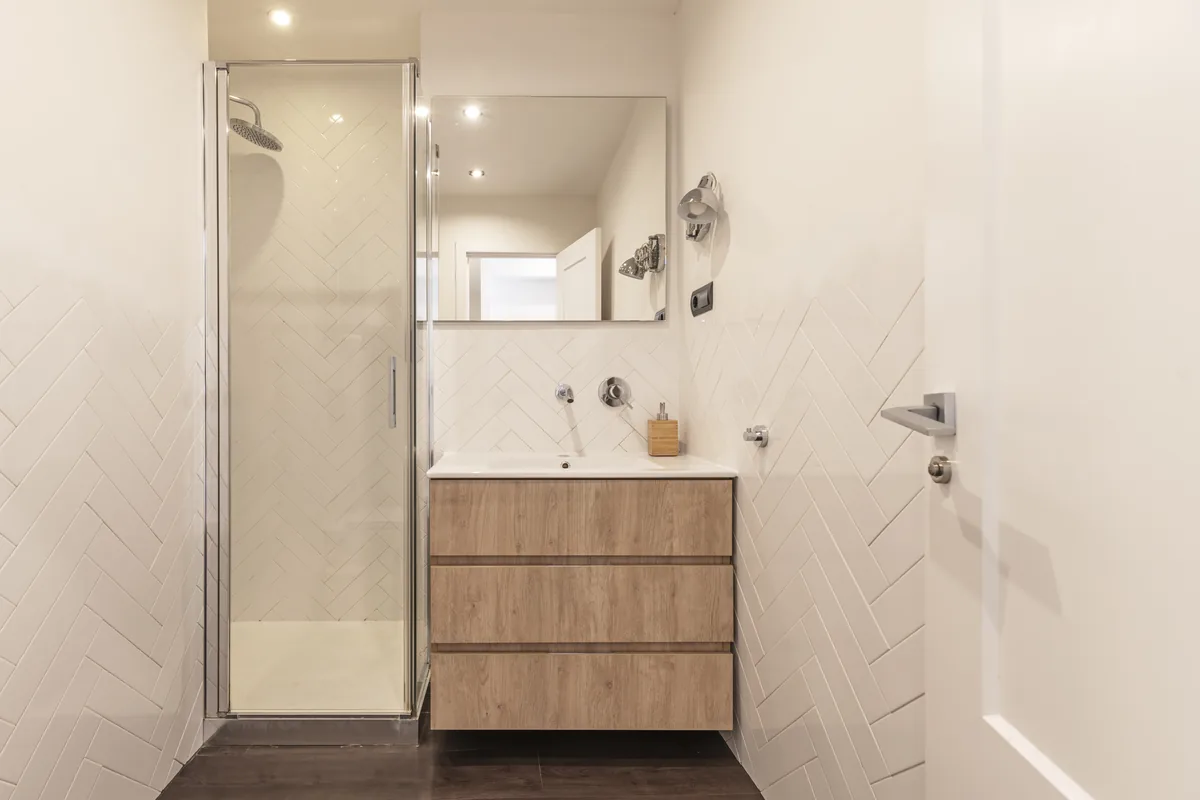 Come ristrutturare un bagno con budget ridotto Bagno compatto con box doccia in cristallo, mobile lavabo sospeso e specchio, esempio di come ristrutturare un bagno con budget ridotto